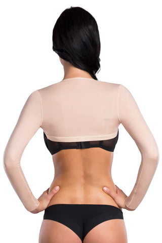 Woman wearing a beige shapewear top and black underwear on a white background